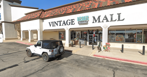 A white Jeep parked outside a building labeled "Vintage Mall," featuring a tiled roof and large storefront windows.