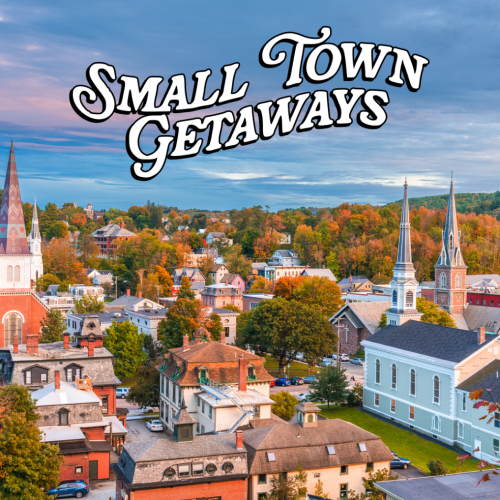 A scenic view of a charming small town with colorful autumn foliage and historic buildings under a blue sky.
