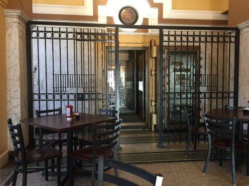Interior of a restaurant featuring a gated entrance, with tables and chairs in the foreground.