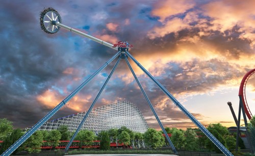 A towering amusement park ride against a dramatic sunset, with a large wooden coaster in the background.
