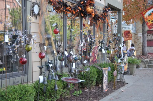 A storefront display featuring various decorative items, including ornaments and garden art, adorned for fall.