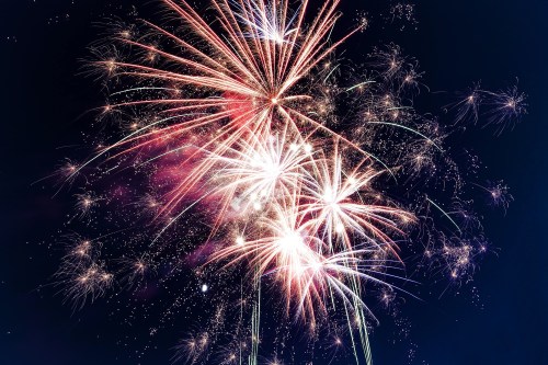 Colorful fireworks explode in the night sky, creating a vibrant display of light and sparks.