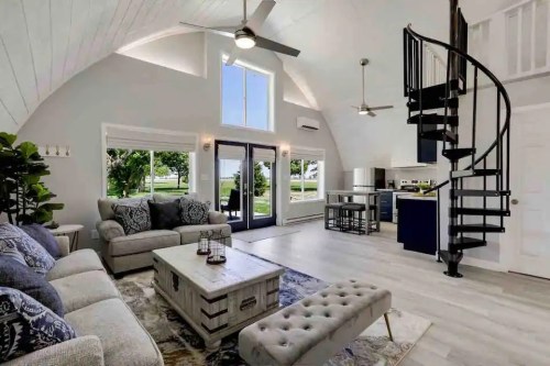 Bright, modern living room with a spiral staircase, large windows, and stylish furniture overlooking a scenic view.