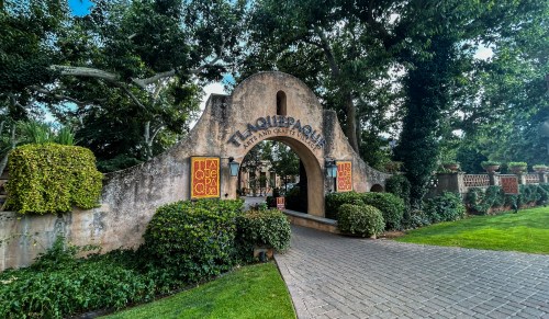 Entrance archway of a restaurant surrounded by lush greenery and decorative planters.