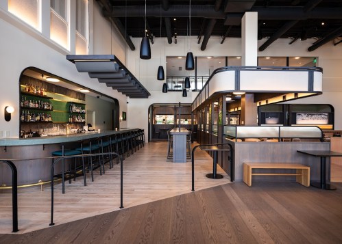 Modern restaurant interior featuring a bar, sleek furniture, and stylish lighting in a spacious layout.
