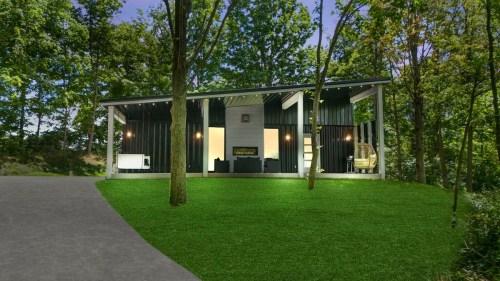 Modern house surrounded by trees, featuring large windows and a grassy lawn, set in a serene outdoor environment.