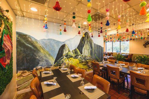 Colorful restaurant interior featuring a mural of mountains, decorative lights, and tables set for dining.