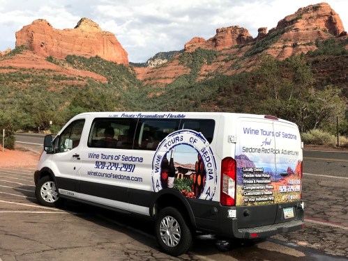 A van advertising wine tours in Sedona, parked with red rock formations in the background.