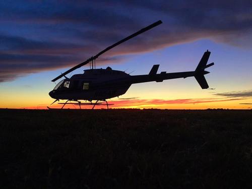 Silhouette of a helicopter against a vibrant sunset sky with colorful clouds.