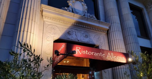A restaurant entrance with a red awning reading "Ristorante Allegria," featuring ornate architectural details.