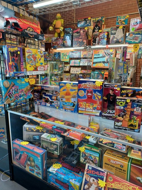 A colorful display of vintage toys and games in a store, featuring action figures, board games, and collectibles.