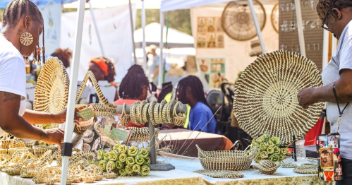 Two artisans showcase handmade woven crafts at a vibrant outdoor market, surrounded by colorful displays and visitors.