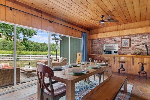 Cozy dining area with wooden accents, a large table set for a meal, and sliding glass doors opening to a scenic view.