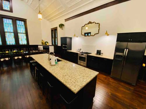 Modern kitchen with a large granite island, black cabinets, stainless steel appliances, and elegant lighting.