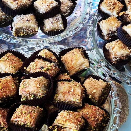 A close-up of assorted baklava pieces on decorative trays, showcasing layers of pastry and nuts.