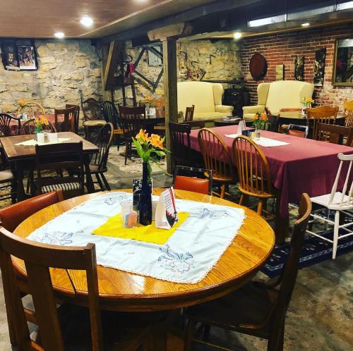 Cozy restaurant interior with wooden tables, colorful tablecloths, and floral centerpieces in a rustic setting.