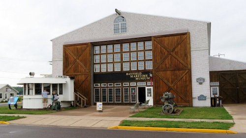 Exterior of the Bayfield Maritime Museum featuring large wooden doors and a small ticket booth.