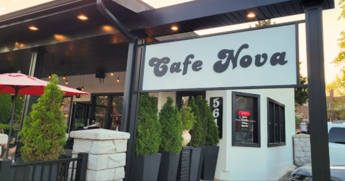 Exterior of Cafe Nova with a sign, outdoor seating, and greenery in planters.