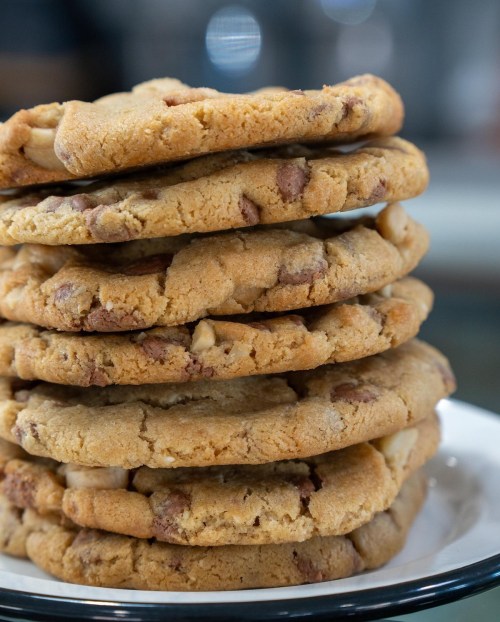 A stack of freshly baked chocolate chip cookies on a white plate.