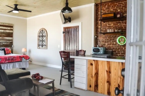 Cozy interior featuring a bed, bar area, and rustic decor with exposed brick and wooden accents.