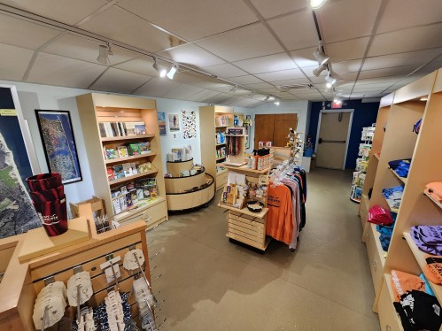 A well-lit store interior featuring shelves of merchandise, clothing, and travel guides in a spacious layout.