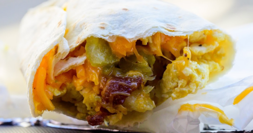 Close-up of a burrito filled with scrambled eggs, cheese, and green peppers wrapped in a soft tortilla.