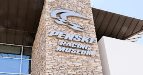 Sign for the Penske Racing Museum, featuring a stone facade and modern architectural design.