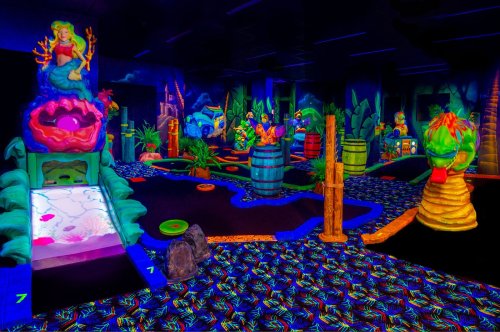 A vibrant glow-in-the-dark mini-golf course featuring whimsical underwater themes and colorful obstacles.