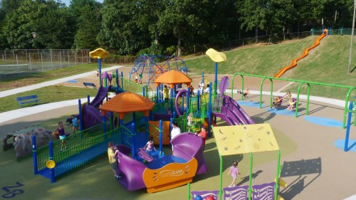 A colorful playground with slides, climbing structures, and children playing on a sunny day.