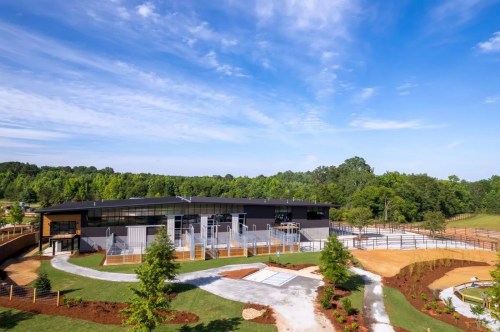 A modern building surrounded by landscaped grounds, trees, and a clear blue sky.
