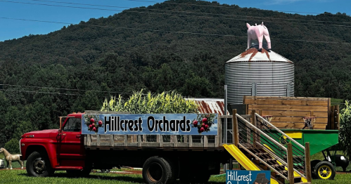 a haywagon carrying corn next to a silver silo with a pig on it at hillcrest orchards in ellijay georgia