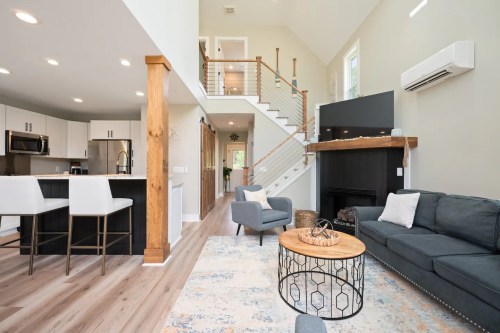 Modern living room with a cozy sofa, coffee table, and staircase leading to an upper level in a bright, open space.