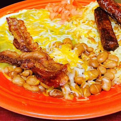 A colorful plate featuring bacon, cheese, beans, hash browns, and sausage, garnished with diced tomatoes.