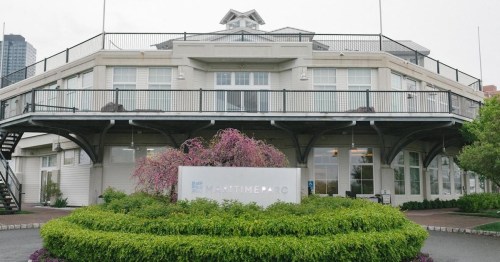 A modern building with a balcony, surrounded by greenery and flowers, featuring a sign that reads "Maritime Parc."