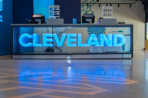 A modern reception desk with a glowing blue "CLEVELAND" sign and a sleek, minimalist design.