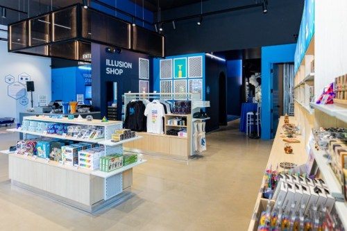 A modern retail space featuring shelves of merchandise, including games and apparel, in a blue and black color scheme.