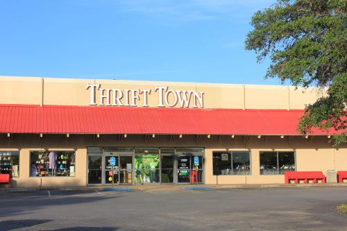Exterior of Thrift Town store with a red awning, large windows, and a clear blue sky in the background.