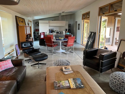 A modern living space featuring a mix of furniture, including a leather sofa, chairs, and a dining area in the background.