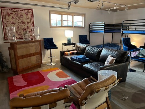 A cozy room with a leather sofa, bunk beds, colorful rug, and modern furniture, featuring warm lighting and decor.