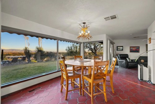 Bright dining area with a wooden table and chairs, large windows showcasing a scenic outdoor view.
