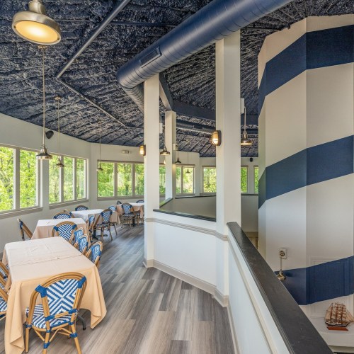 Bright dining area with blue and white decor, large windows, and tables set for guests.