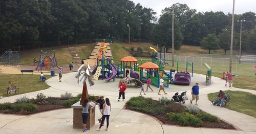 A vibrant playground with children playing, slides, climbing structures, and families enjoying the outdoor space.