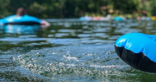 Close up of blue tubes going down a natural lazy river.