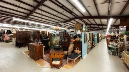A spacious antique store interior with various vintage furniture and decor displayed along the aisles.