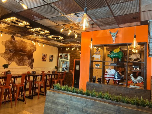 A cozy restaurant interior with rustic decor, warm lighting, and animal-themed artwork on the walls.