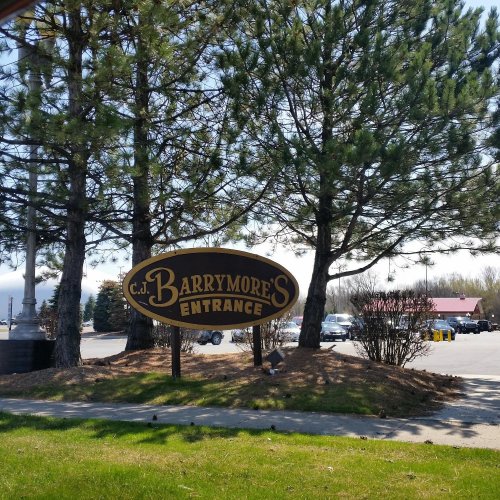 Sign for C.J. Barrymore's entrance, surrounded by trees and a parking lot on a sunny day.