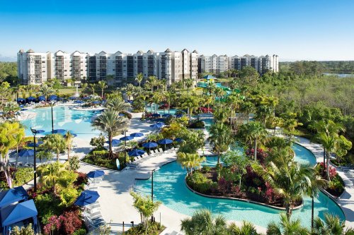 A vibrant resort with winding pools, lush landscaping, and modern buildings under a clear blue sky.
