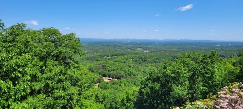 A panoramic view of lush green hills and valleys under a clear blue sky.