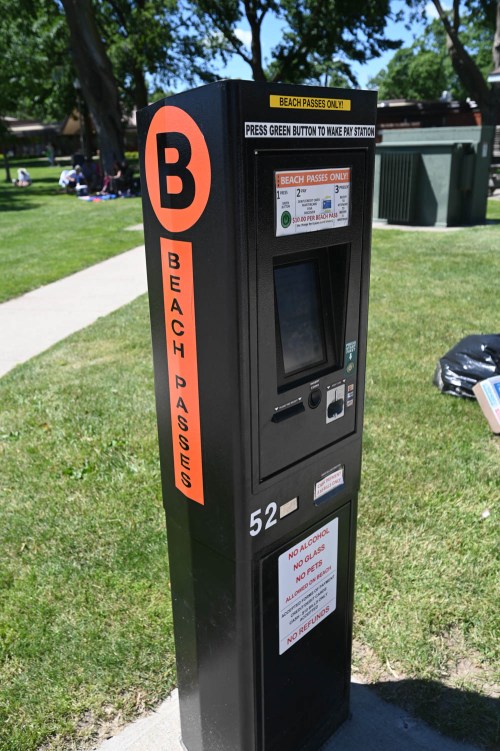 A beach pass vending machine in a park, featuring a touchscreen and instructions for purchasing passes.