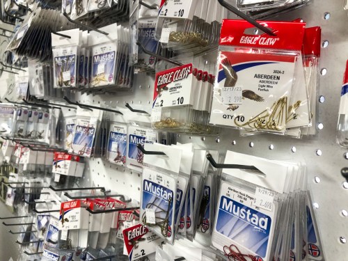 A display of various fishing hooks from brands like Eagle Claw and Mustad, organized on a pegboard.
